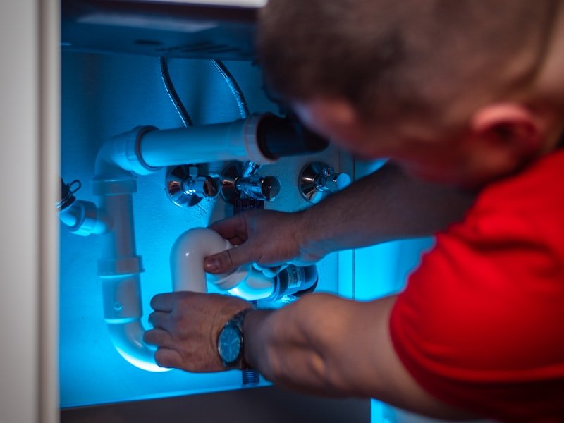Plumber working on a pipe inside a cabinet